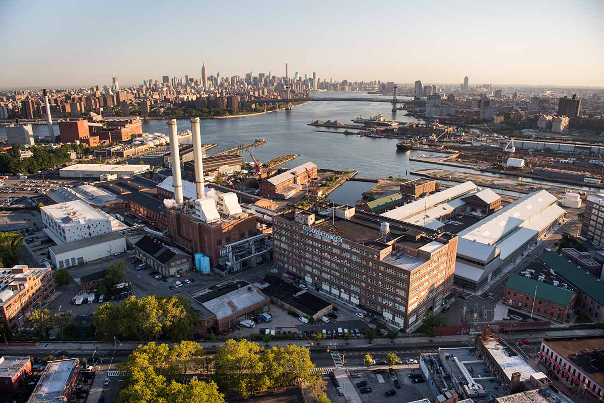 Over sky veiw of brooklyn navy yard, large retangle buildings, ships, and ports